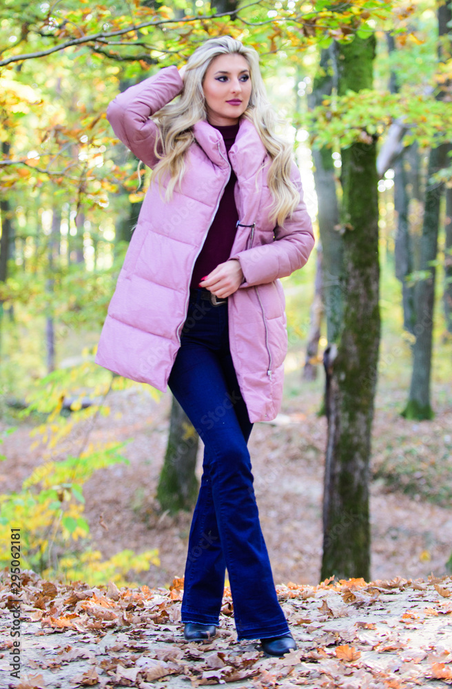 Girl fashionable blonde walk in autumn forest. Jackets everyone should have. Best puffer coats to buy. How to rock puffer jacket like a star. Puffer fashion concept. Woman wear warm pink jacket