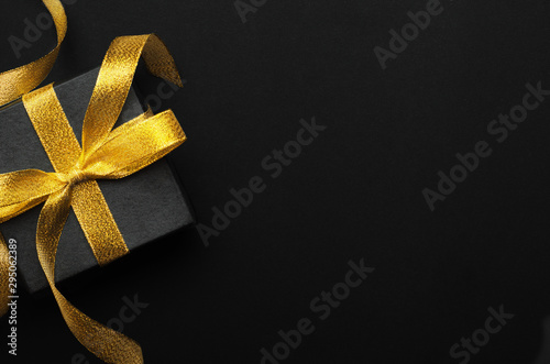 Holiday gift box with bow top view background. Birthday surprise, Christmas present and golden tape close up. Decorative backdrop with copyspace. Festive composition, surprise concept photo