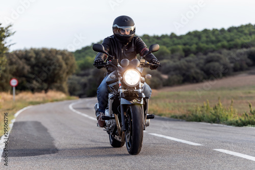 Young man biker having fun driving the empty highway on a motorcycle tour journey. © nenetus