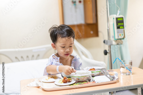 A patient boy is eatting food while he sick in the hospital.