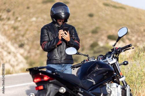 Man biker talking on the phone to the insurance of his motorcycle after having suffered a breakdown on the road.