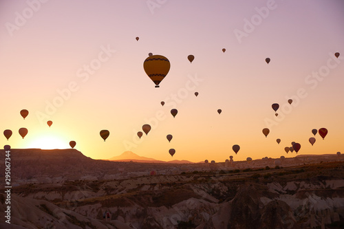 sunrise photo in Cappadocia with air balloons in the sky over sandy hills