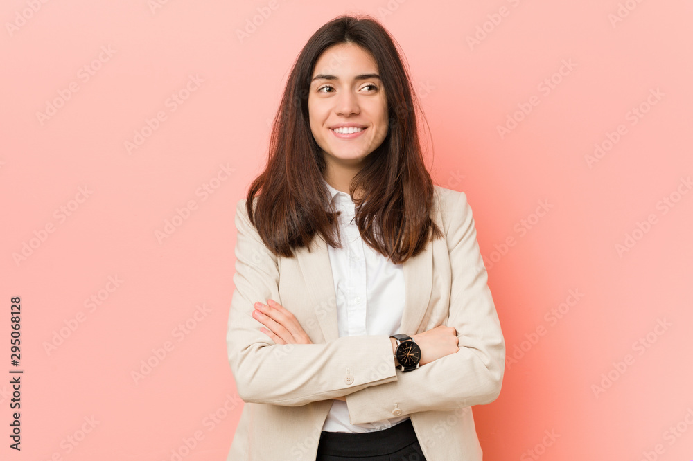 Young brunette business woman against a pink background smiling confident with crossed arms. Young brunette business woman against a pink background smiling confident with crossed arms.