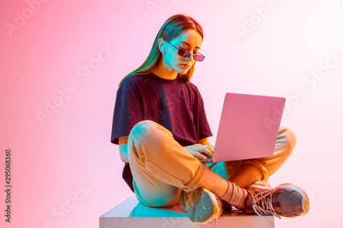 Modern Girl with laptop, tablet computer. Free creativity. A young blogger makes a Home office. Colored Neon light and background. photo