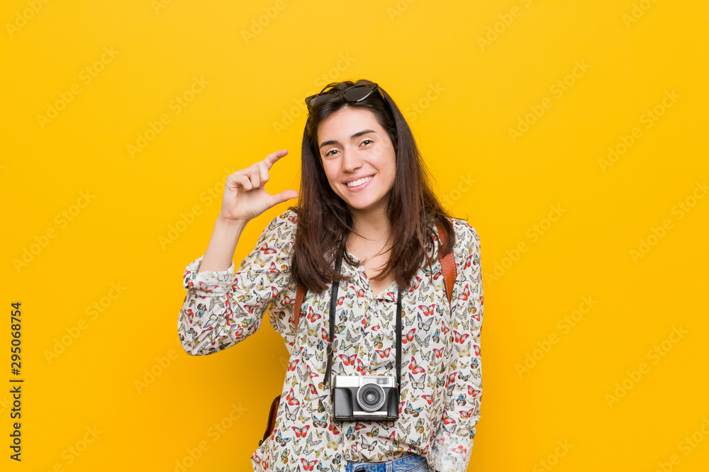Young brunette traveler woman holding something little with forefingers, smiling and confident. Young brunette traveler woman holding something little with forefingers, smiling and confident.