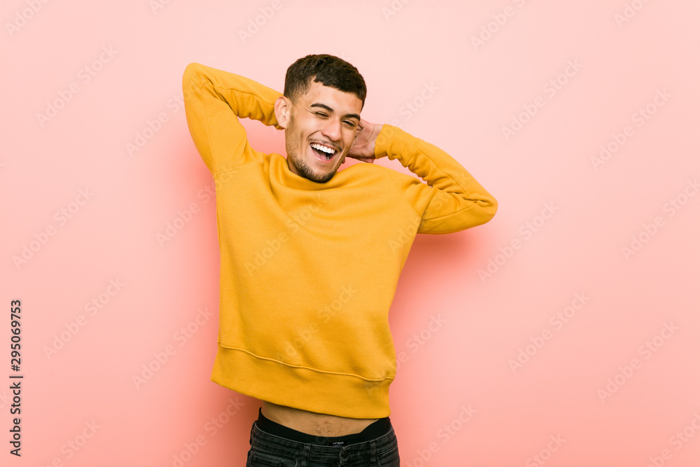 Young hispanic man stretching arms, relaxed position. - obrazy, fototapety, plakaty 