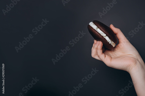 Close up Traditional chocolate and Pumpkin Whoopie pies filled made with vanilla cream in woman hand photo