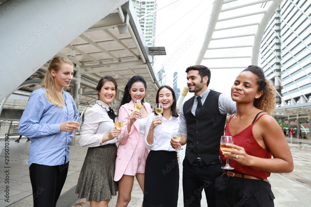 Successful multiethnic business people are clinking glasses of champagne with smiling while celebrating outdoor