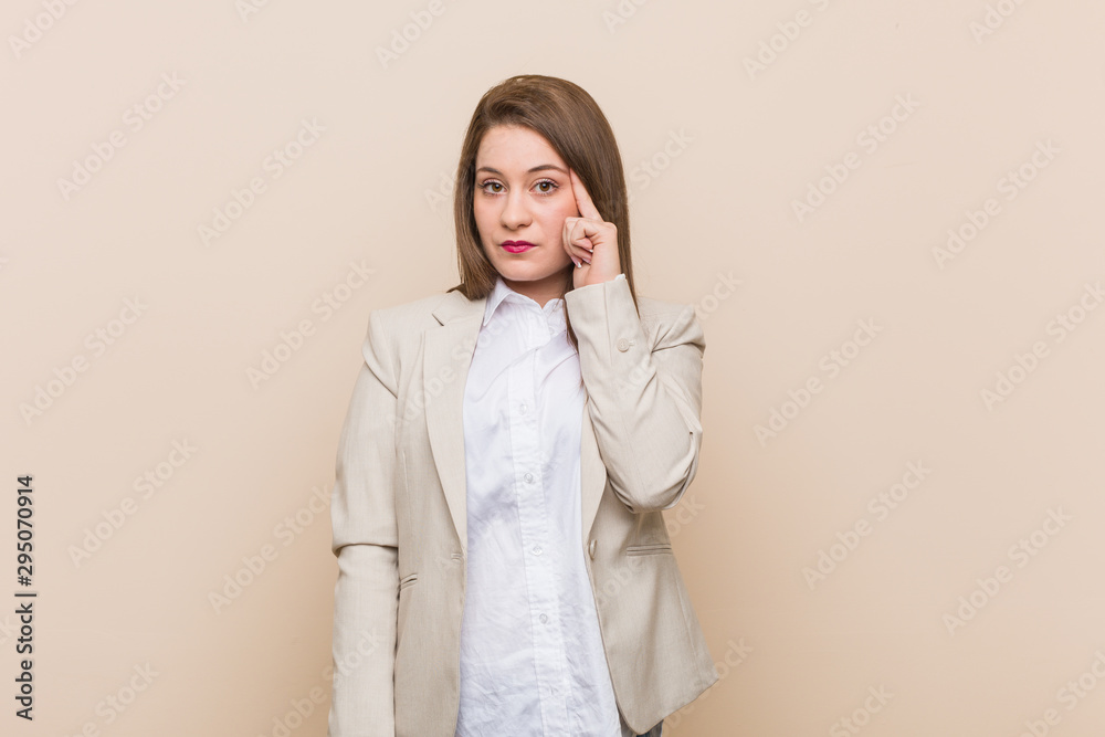 Young business woman pointing temple with finger, thinking, focused on a task. Young business woman pointing temple with finger, thinking, focused on a task.