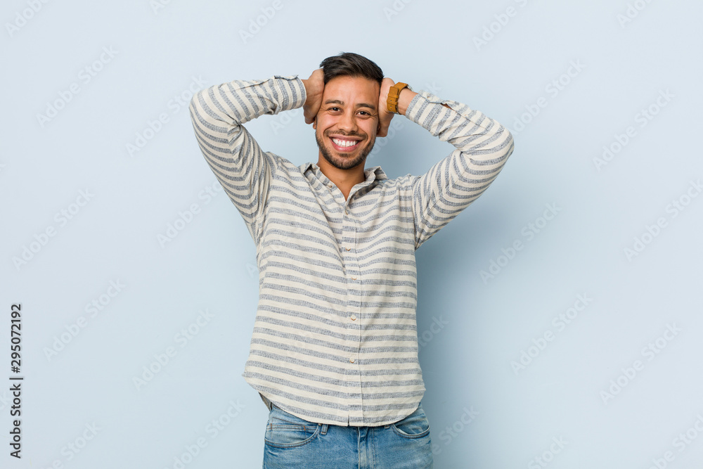 Fototapeta premium Young handsome filipino man laughs joyfully keeping hands on head. Happiness concept.