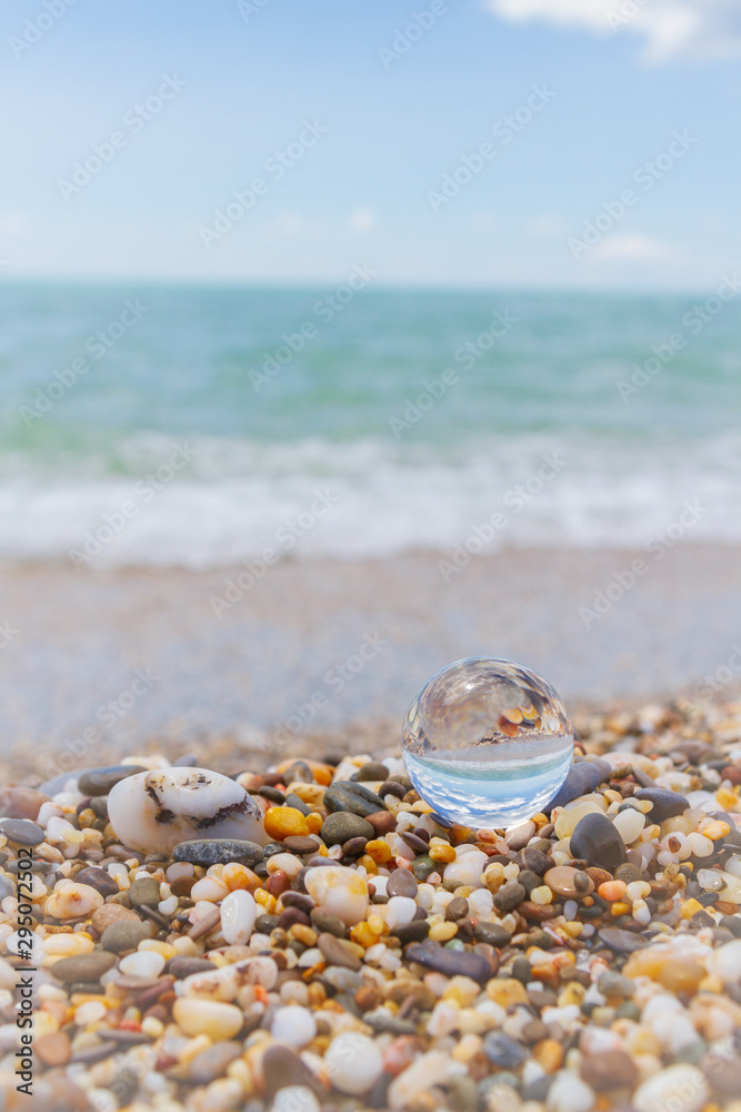Glass round ball on the beach reflects the sea in summer Glass round ball on the beach reflects the sea in summer
