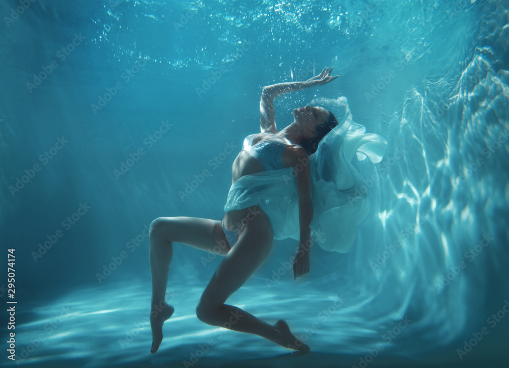 Fashion art photo of beautiful woman swimming and posing underwater