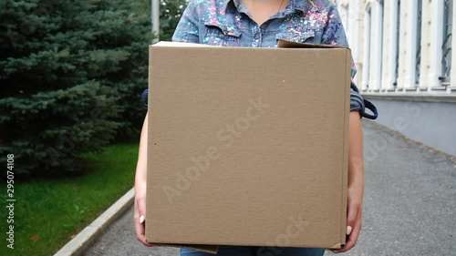 Woman carrying a cardboard box and walking outdoor