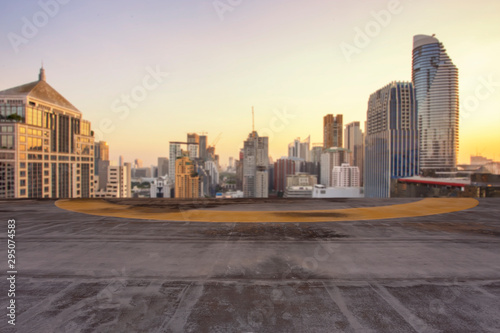 The cement floor with blurred of cityscape background in the evening at Bangkok , Thailand. Cement floor on the roof with sunset over the building in capital.