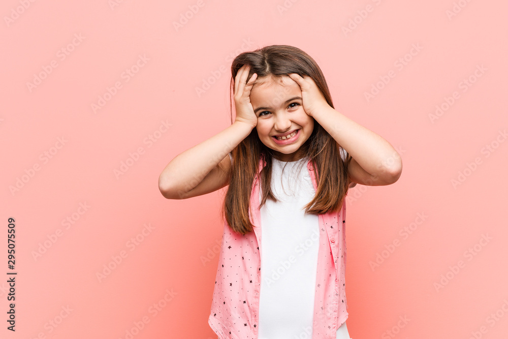 Cute little girl laughs joyfully keeping hands on head. Happiness concept. Cute little girl laughs joyfully keeping hands on head. Happiness concept.