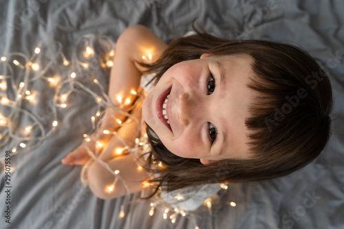 Little girl is playing with New Year's garlands. A child among the New Year's lights