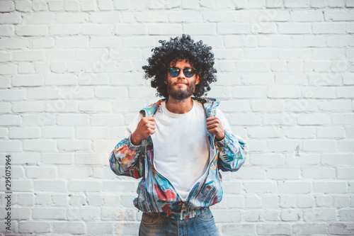 Stylish young man in a retro jacket. Fashion trends of 90s. Handsome hipster guy with beard with curly hair. photo