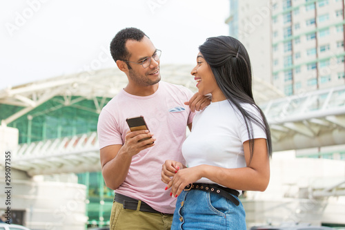 Free Download Joyful friends looking at each other on street. Cheerful young people with modern phone posing. Technology concept - GFXLoad