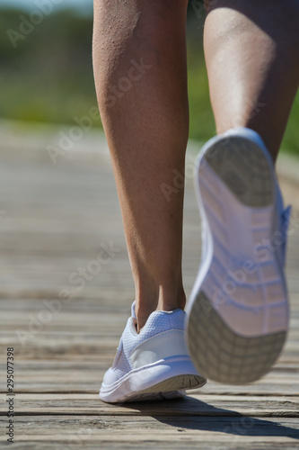 Rear view of person running wearing white shoes in which only the person's legs are seen with the background out of focus.