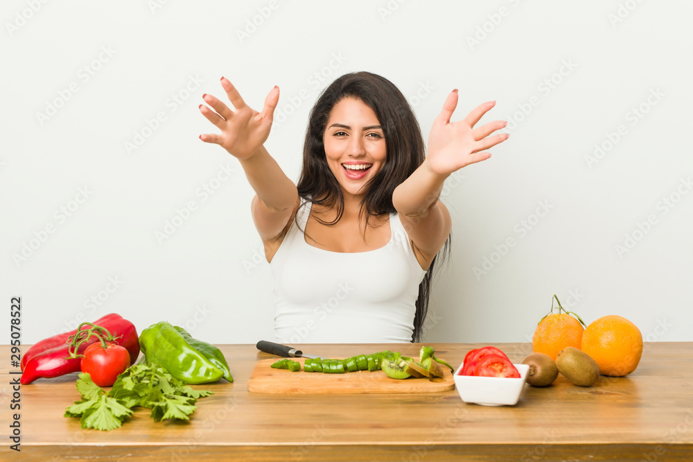 Young curvy woman preparing a healthy meal feels confident giving a hug to the camera. Young curvy woman preparing a healthy meal feels confident giving a hug to the camera.
