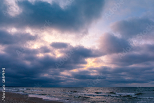 sandy beach by the sea with gloomy cloudy weather in the purple light of sunset