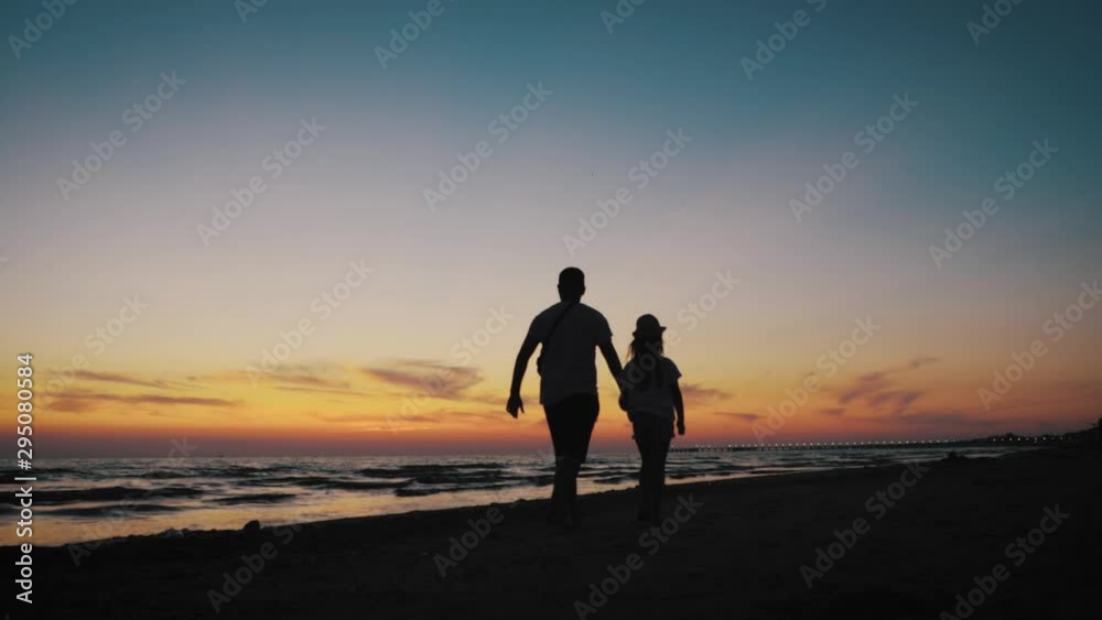 Silhouettes father and daughter play on the beach at sunset. Concept of friendly family, travel, lifestyle. Silhouettes father and daughter play on the beach at sunset. Concept of friendly family, travel, lifestyle.