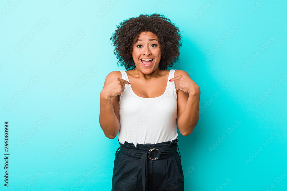 Young african american woman surprised pointing with finger, smiling broadly.