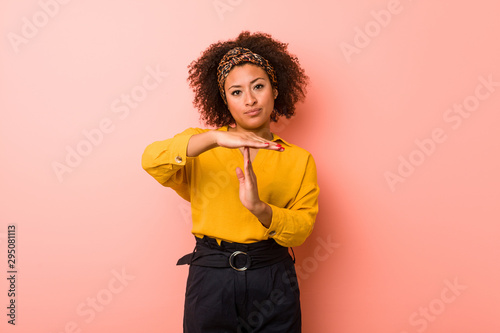 Young african american woman against a pink background showing a timeout gesture. photo