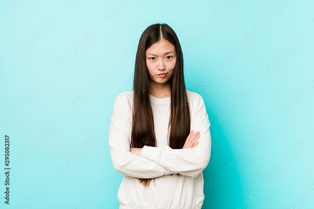 Young pretty chinese woman frowning face in displeasure, keeps arms folded. Young pretty chinese woman frowning face in displeasure, keeps arms folded.