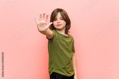 Little boy standing with outstretched hand showing stop sign  preventing you.