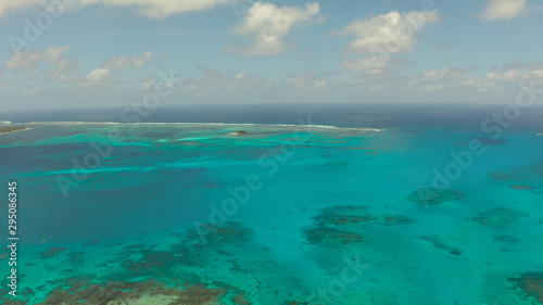 Fototapeta Naklejka Na Ścianę i Meble -  Top view of turquoise water of the atoll against the backdrop of the tropical island and sky with clouds. Travel concept.