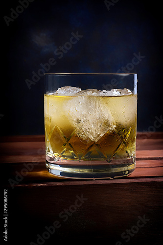 WHISKEY GLASS WITH ICE AND ON DARK BLUE BACKGROUND WITH TEXTURE
