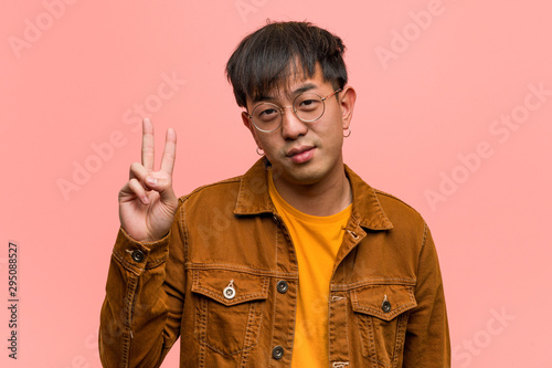 Young chinese man wearing a jacket showing number two