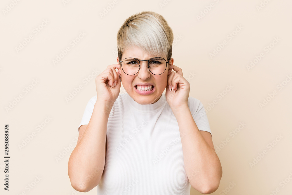 Young authentic natural woman wearing a white shirt covering ears with hands. Young authentic natural woman wearing a white shirt covering ears with hands.