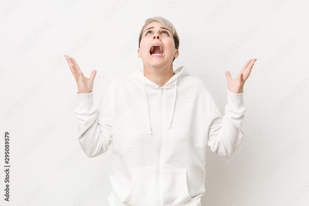 Young curvy woman wearing a white hoodie screaming to the sky, looking up, frustrated. Young curvy woman wearing a white hoodie screaming to the sky, looking up, frustrated.