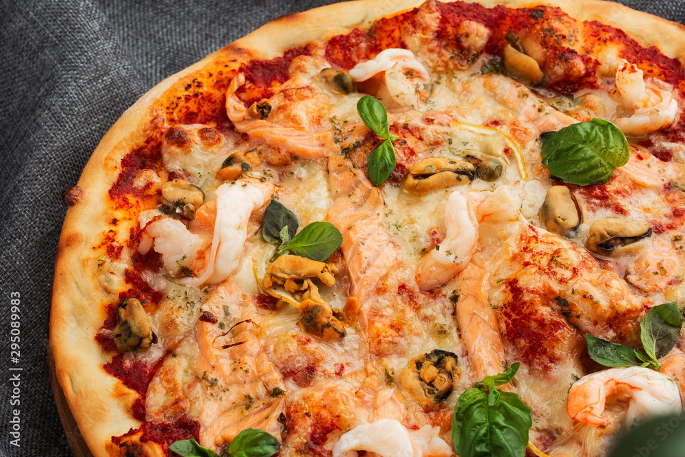 Seafood Italian pizza with shrimp,squid, mussels, fresh herbs and mozzarella on a crusty base viewed from above on Gray background. Horizontal photo. Seafood Italian pizza with shrimp,squid, mussels, fresh herbs and mozzarella on a crusty base viewed from above on Gray background. Horizontal photo.