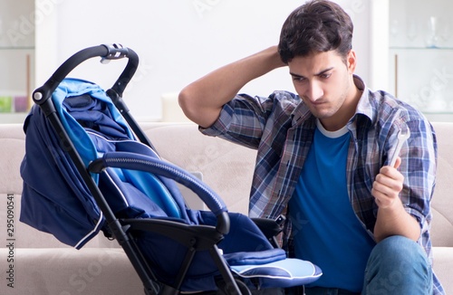 Young father assembling baby pram at home