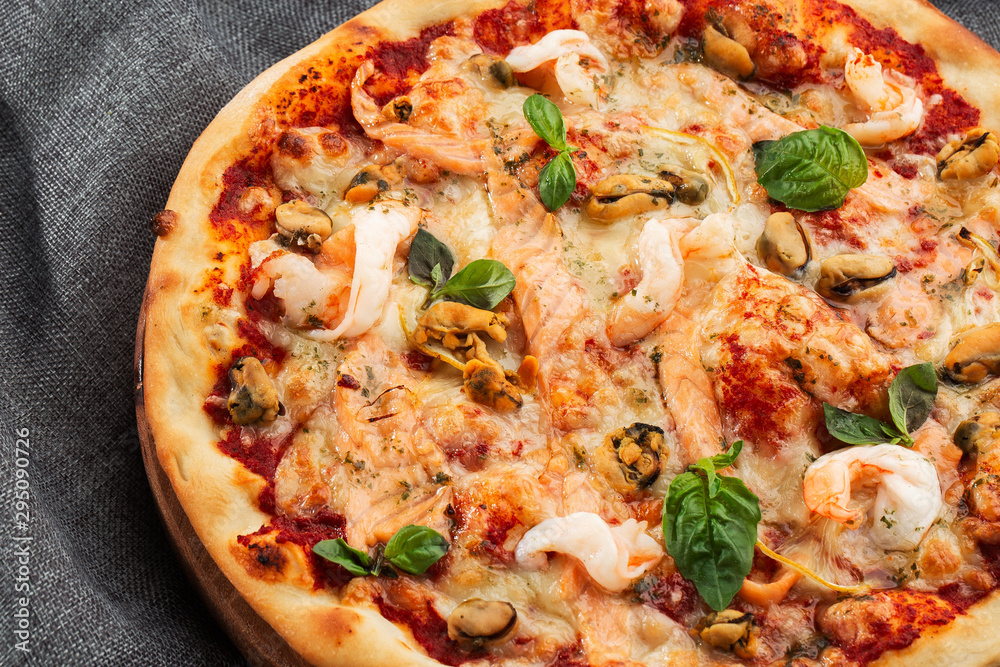 Seafood Italian pizza with shrimp,squid, mussels, fresh herbs and mozzarella on a crusty base viewed from above on Gray background. Horizontal photo. Seafood Italian pizza with shrimp,squid, mussels, fresh herbs and mozzarella on a crusty base viewed from above on Gray background. Horizontal photo.