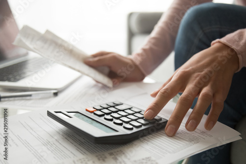Woman using calculator holding bills planning expenses, close up view