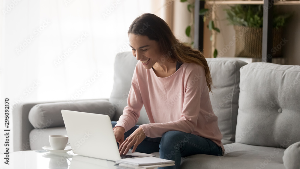 Happy young woman laughing using laptop sitting on sofa Happy young woman laughing using laptop sitting on sofa