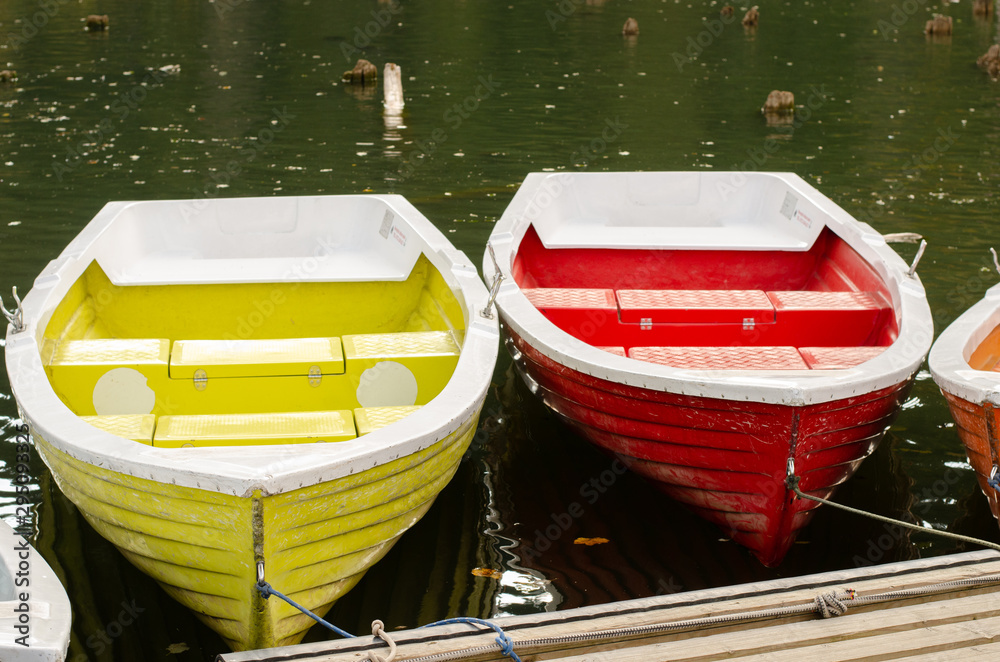Colorful boats docked on the edge of a mountain lake during autumn season. National park trip . Colorful boats docked on the edge of a mountain lake during autumn season. National park trip .