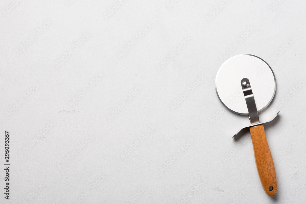 Clean pizza cutter with wooden handle on stucco table top view Clean pizza cutter with wooden handle on stucco table top view