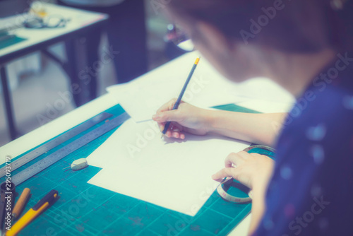 Girl, women design, lacture, drawing something by right hand hold pencil and stationary, mease tape on the table photo