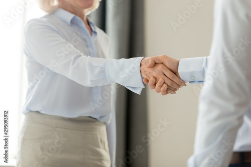 Cropped closeup image middle aged business lady handshake with businessman