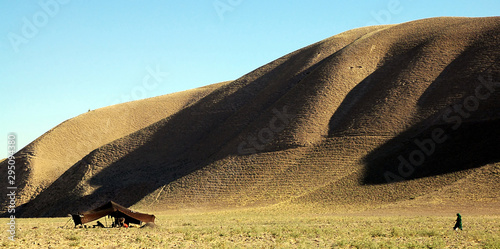 Countryside close to Bala Murghab in Badghis Province on the road to Maymana. Nomads have pitched a tent on the scrubby grassland beneath a hill. A woman walks towards the tent. Western Afghanistan. photo