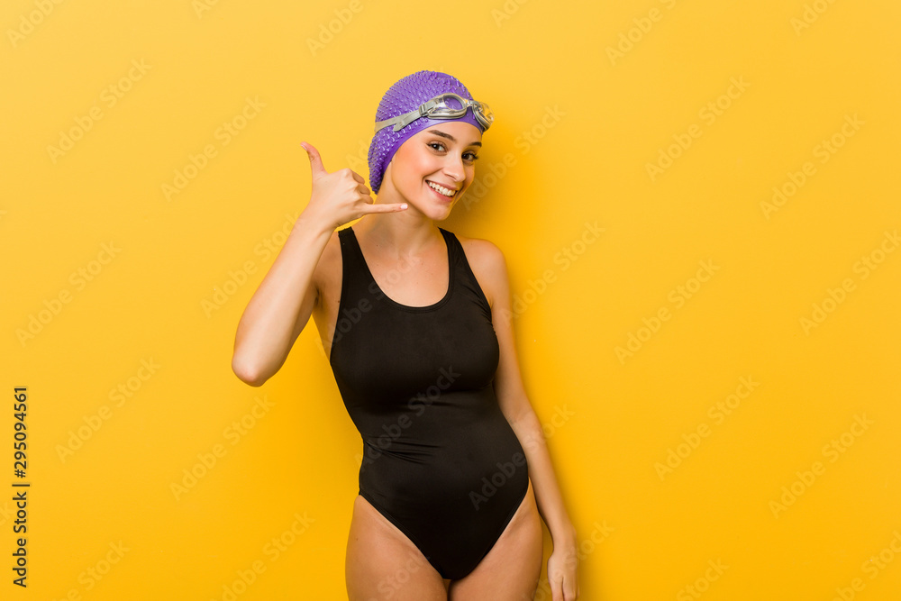 Young swimmer caucasian woman showing a mobile phone call gesture with fingers. Young swimmer caucasian woman showing a mobile phone call gesture with fingers.