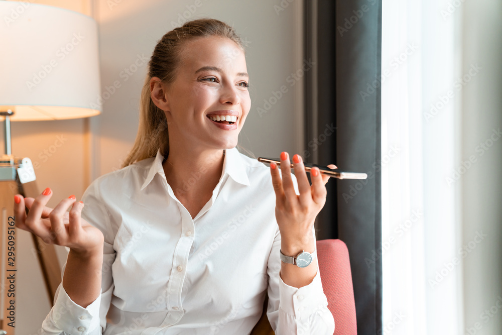 Cheery pretty blonde business woman talking by phone.