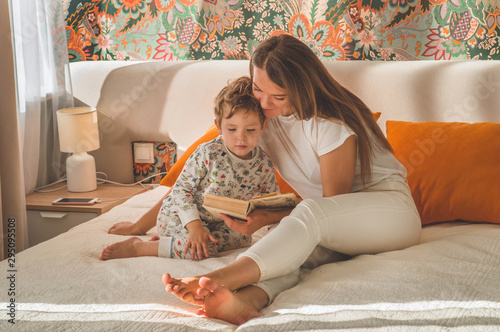 Pretty young mother reading a book to her little son in modern interior photo