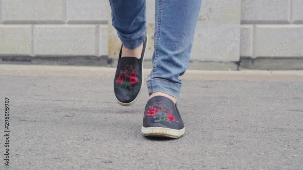 Detail of woman's feet walking through city on pavement Detail of woman's feet walking through city on pavement