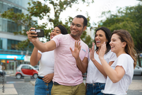 Smiling friends waving to camera phone. Group of cheerful young people posing for selfie. Concept of self portrait